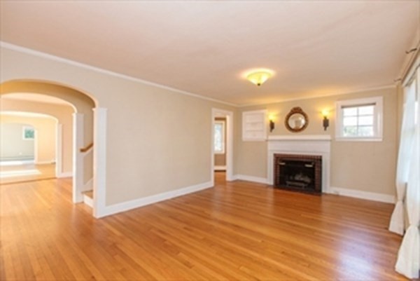 82 Beechwood Road Wellesley, MA 02482 - Photo 6 of 25 a view of an empty room with wooden floor a fireplace and a window
