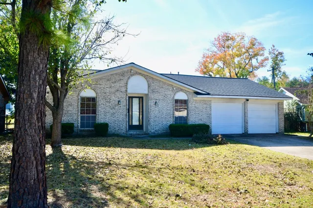 a front view of house with yard and trees in the background
