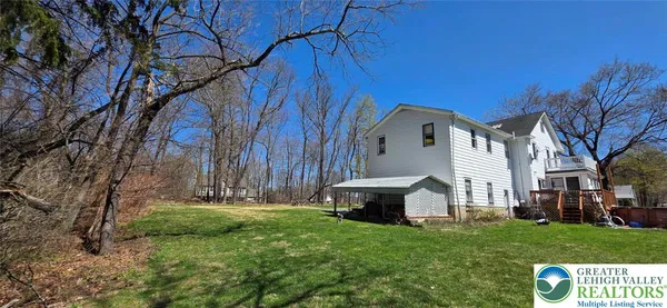 a view of house with yard and trees in the background