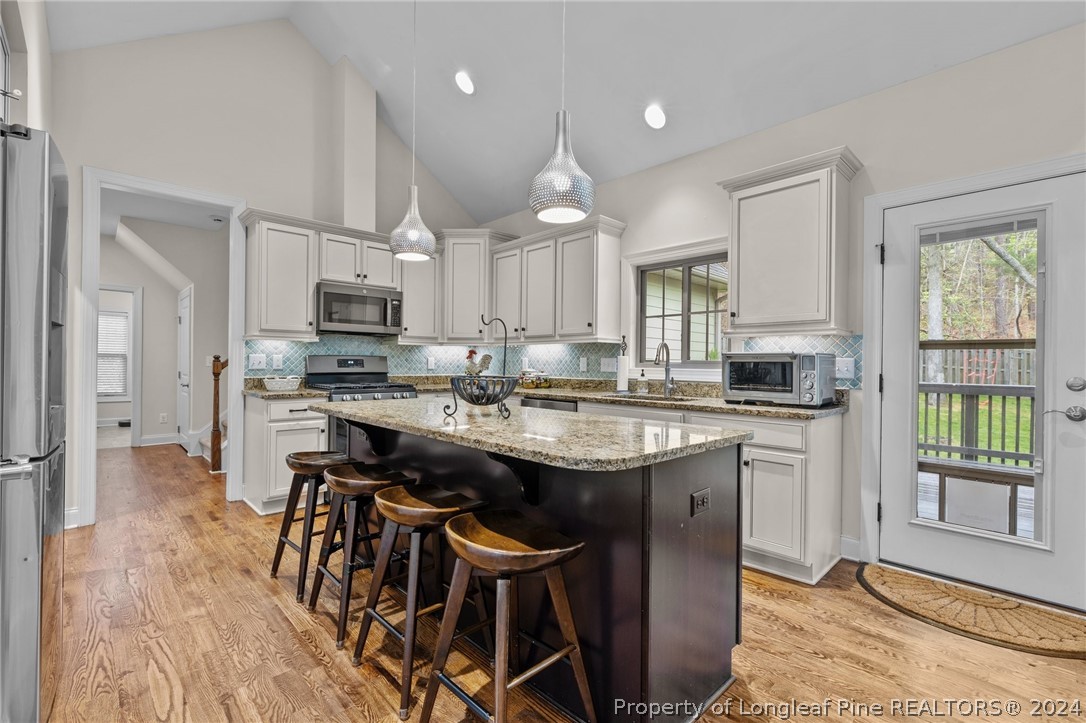 208 Rob Roy Road Southern Pines, NC 28387 - Photo 14 of 48 a kitchen with kitchen island granite countertop wooden floor and stainless steel appliances