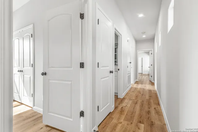 a view of a hallway with wooden floor and a bathroom