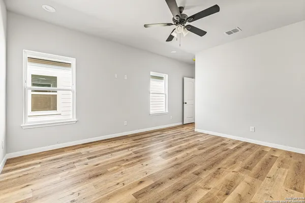 a view of empty room with wooden floor and fan
