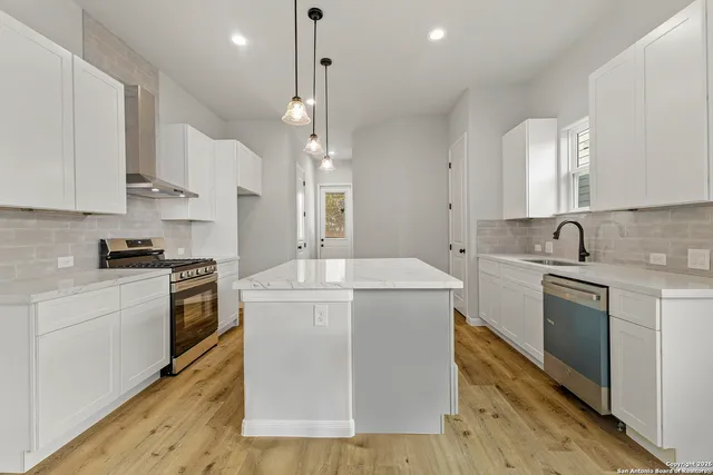 a kitchen with a stove a sink and white cabinets