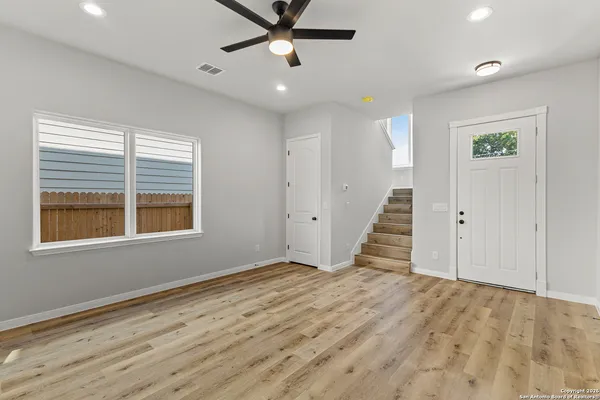 a view of an empty room with wooden floor and a window