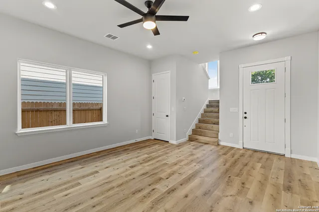 a view of an empty room with wooden floor and a window