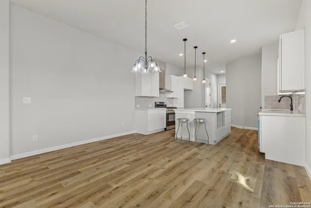 a large room with kitchen island a chandelier and wooden floor