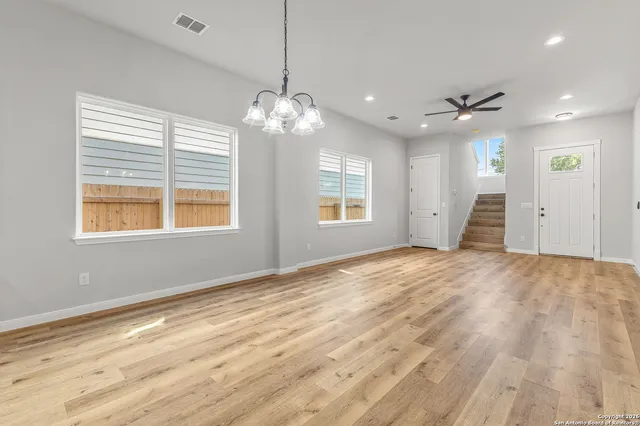 a view of an empty room with a window and wooden floor