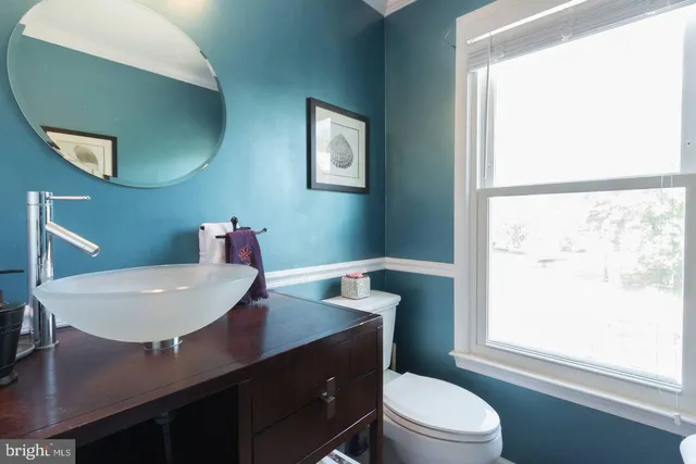 a bathroom with a sink a toilet a window and mirror