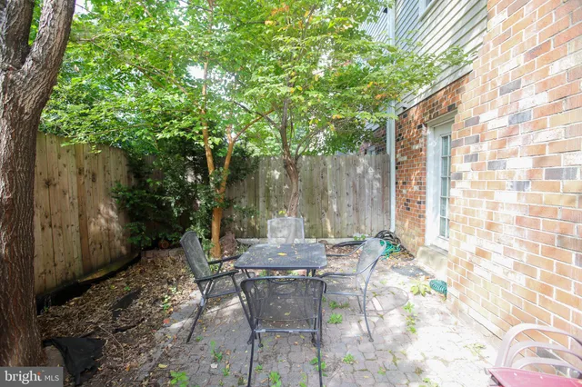 a patio with table and chairs and potted plants
