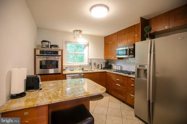 a kitchen with granite countertop a refrigerator and a stove top oven