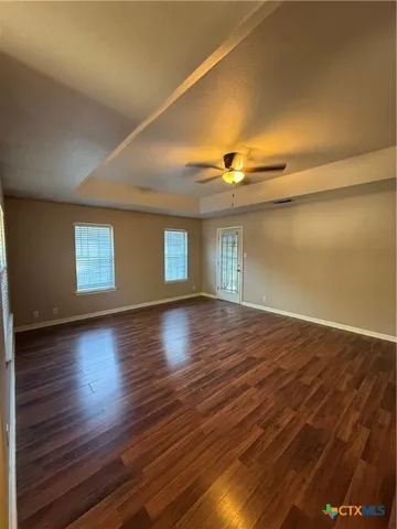 a view of empty room with wooden floor and fan