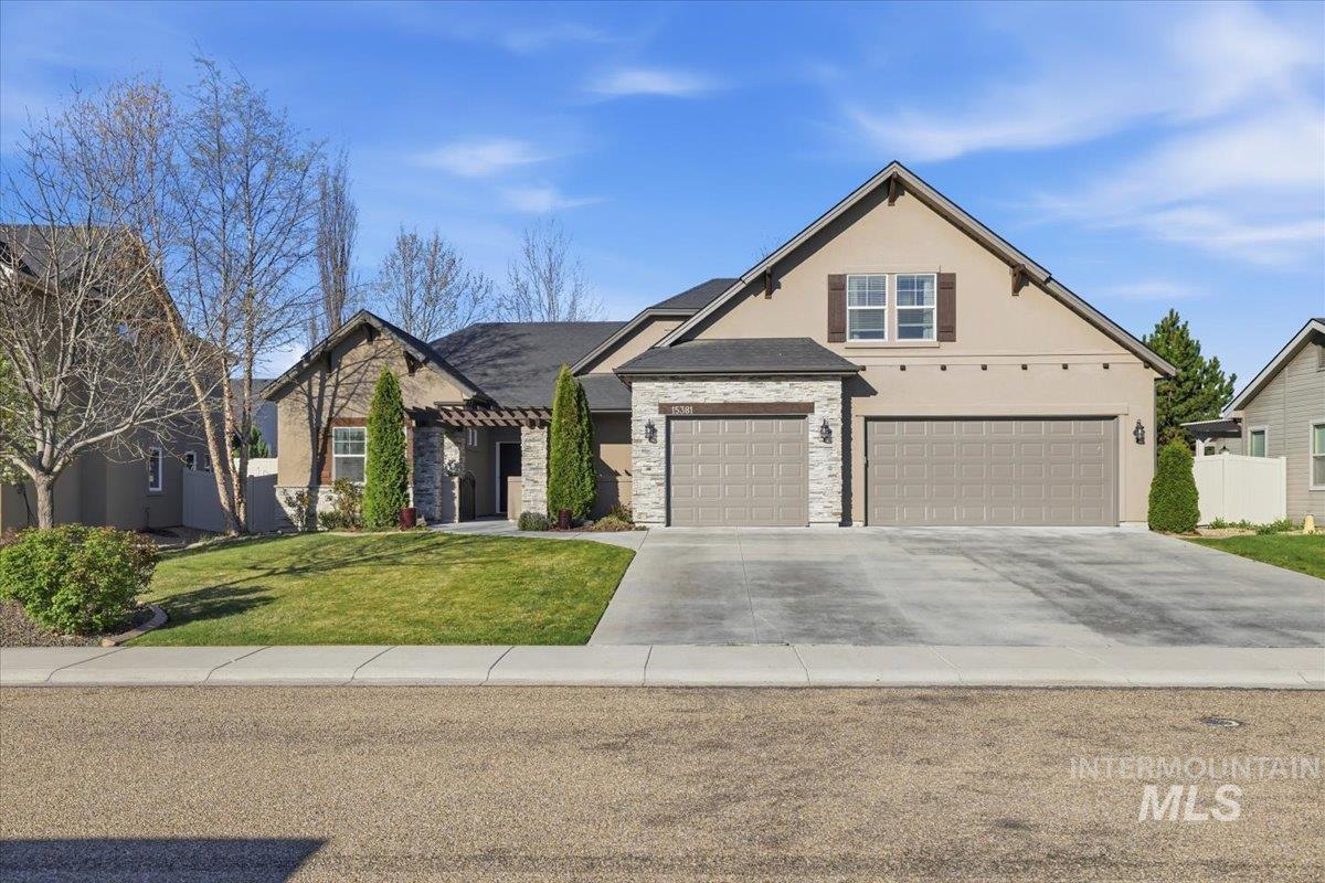 View of front facade with stucco siding, driveway, stone siding, and an attached garage