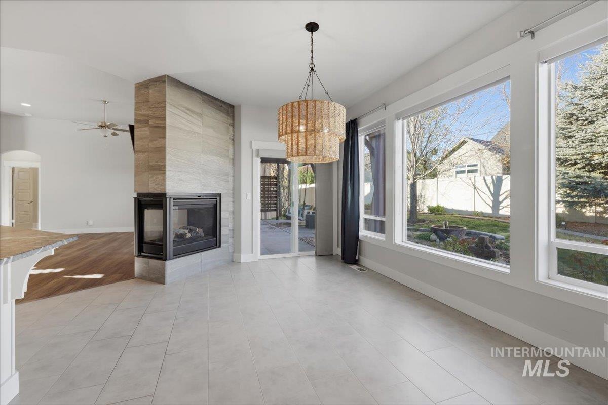 15381 Silver Oak Way Caldwell, ID 83607 - Photo 15 of 48 Unfurnished living room featuring a multi sided fireplace, ceiling fan, a chandelier, and arched walkways
