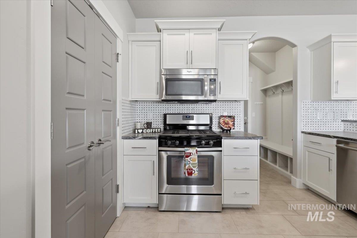 15381 Silver Oak Way Caldwell, ID 83607 - Photo 17 of 48 Kitchen with decorative backsplash, stainless steel appliances, white cabinetry, and dark stone countertops