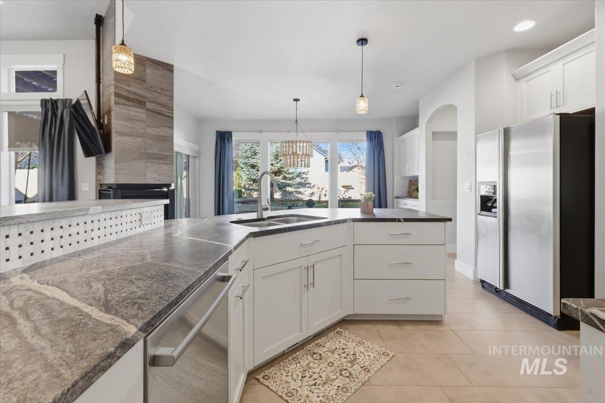 15381 Silver Oak Way Caldwell, ID 83607 - Photo 18 of 48 Kitchen featuring white cabinetry, stainless steel appliances, a chandelier, and light tile patterned floors