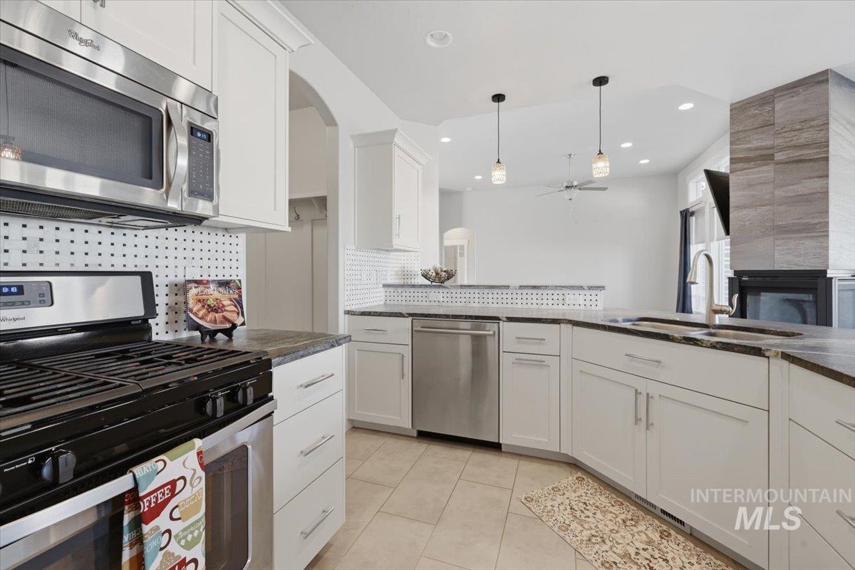 15381 Silver Oak Way Caldwell, ID 83607 - Photo 20 of 48 Kitchen featuring stainless steel appliances, white cabinets, a ceiling fan, tasteful backsplash, and pendant lighting