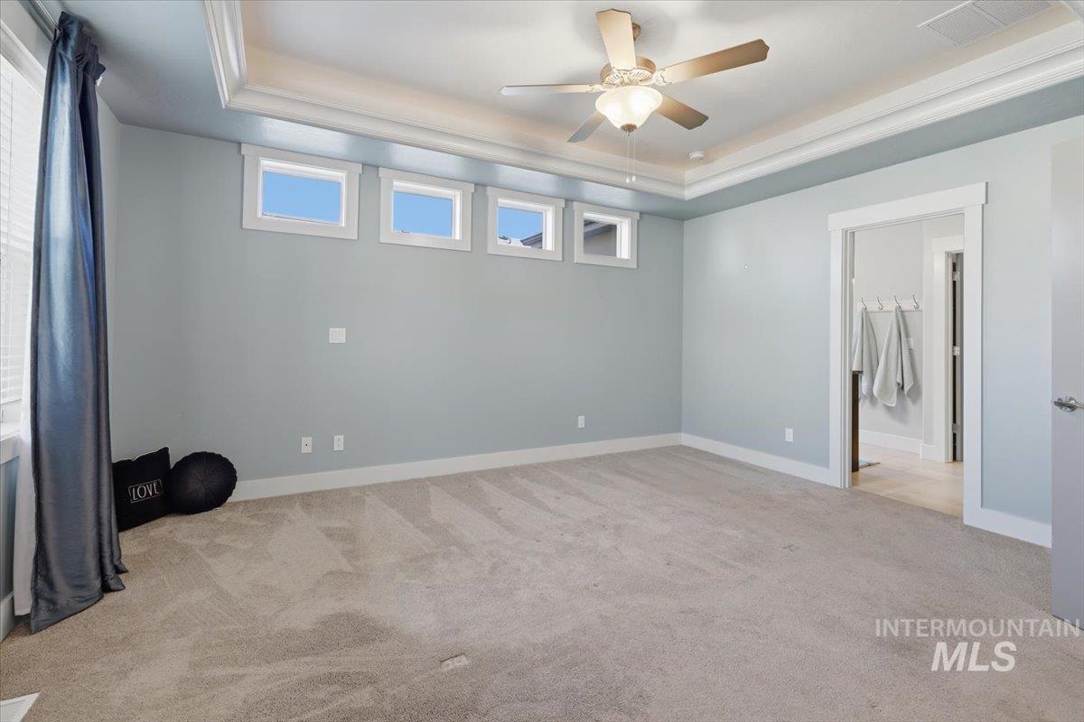 15381 Silver Oak Way Caldwell, ID 83607 - Photo 23 of 48 Unfurnished bedroom with a raised ceiling, light carpet, a ceiling fan, and ensuite bathroom