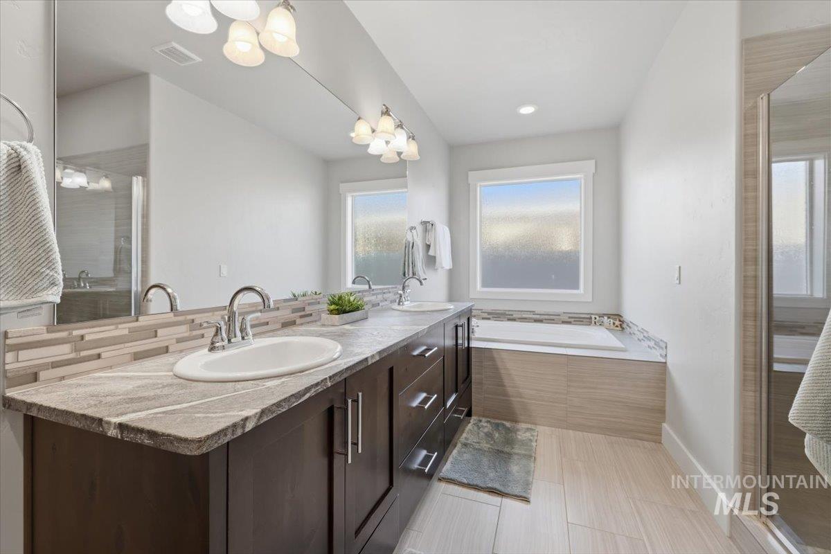 15381 Silver Oak Way Caldwell, ID 83607 - Photo 26 of 48 Full bathroom featuring a stall shower, double vanity, a bath, and backsplash