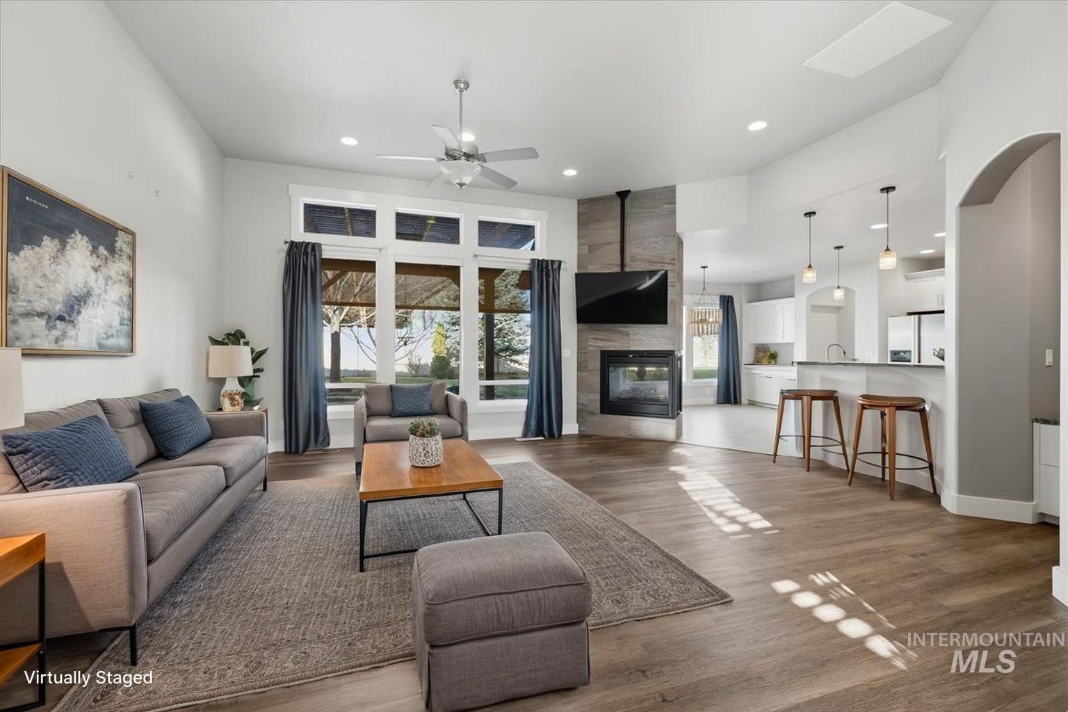 15381 Silver Oak Way Caldwell, ID 83607 - Photo 5 of 48 Living room featuring a fireplace, plenty of natural light, a high ceiling, ceiling fan, and dark wood-style flooring