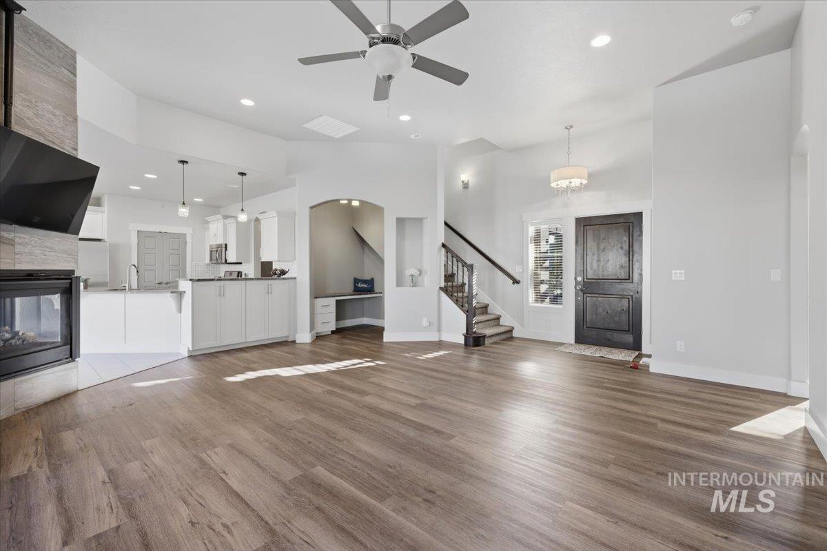 15381 Silver Oak Way Caldwell, ID 83607 - Photo 8 of 48 Unfurnished living room featuring a tiled fireplace, dark wood finished floors, a ceiling fan, recessed lighting, and a high ceiling