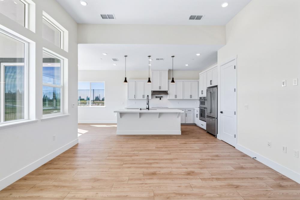 14834 Grace Warren Way Rancho Murieta, CA 95683 - Photo 6 of 21 a large white kitchen with stainless steel appliances kitchen island a large counter top and a wooden floors