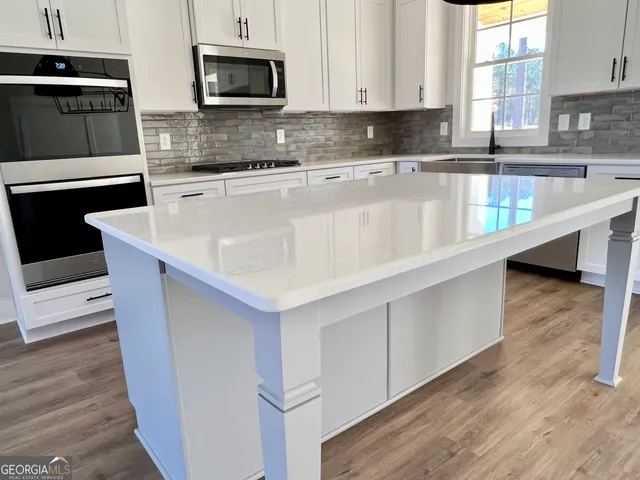 an open kitchen with wooden floor and stainless steel appliances