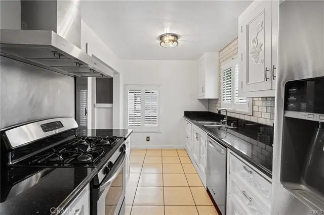 a kitchen with granite countertop stainless steel appliances a sink stove and cabinets