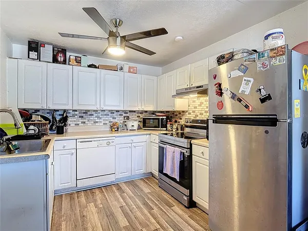 a kitchen with stainless steel appliances granite countertop a refrigerator sink and white cabinets