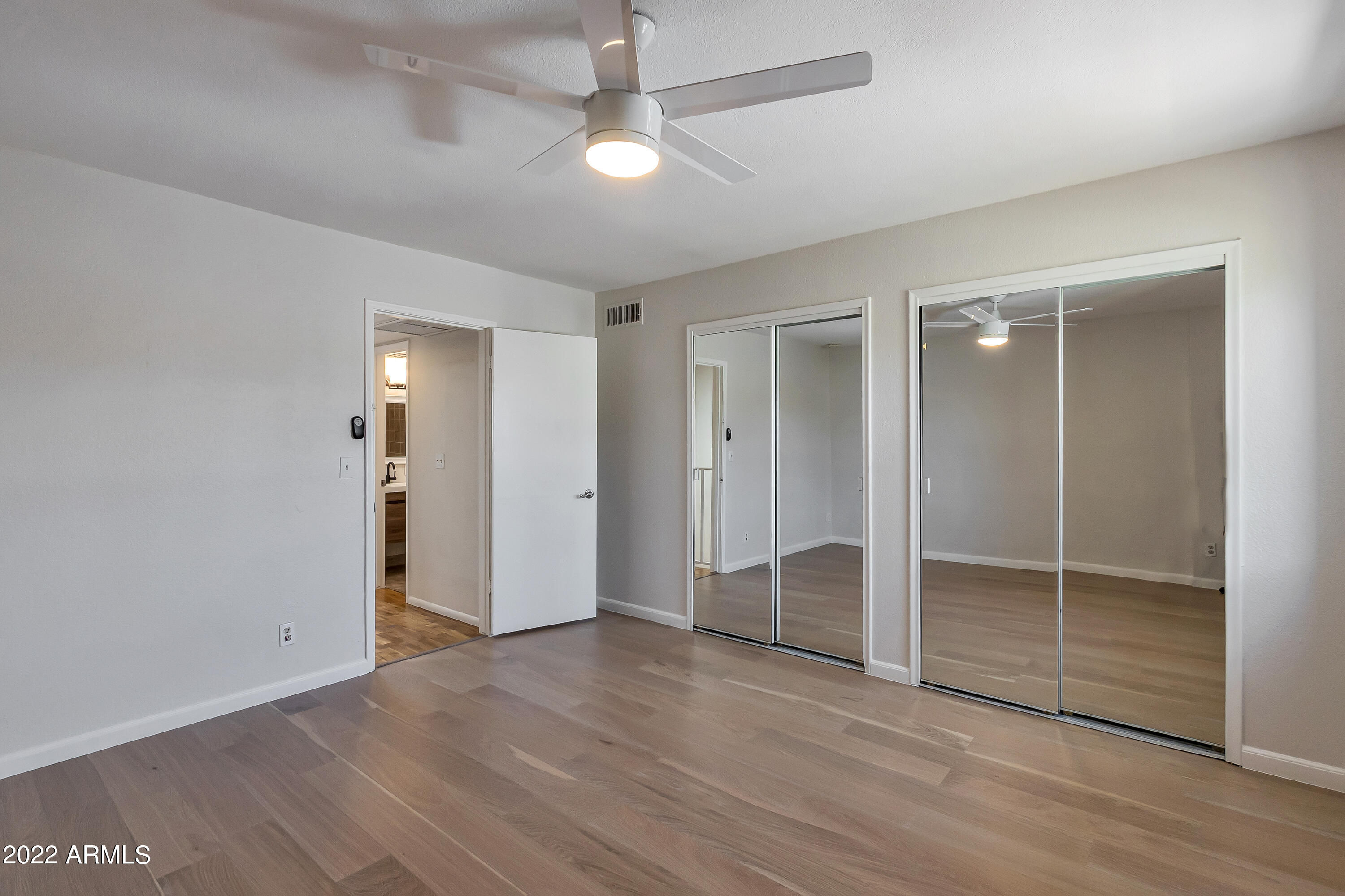 6348 North 7th Avenue, Unit 12 Phoenix, AZ 85013 - Photo 14 of 22 an empty room with wooden floor fan and windows