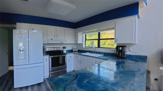 a kitchen with stainless steel appliances granite countertop a stove a sink and a refrigerator