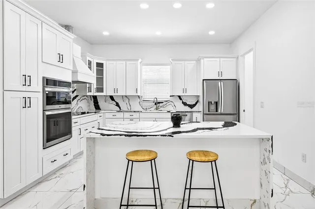 a kitchen with stainless steel appliances granite countertop a white cabinets and a refrigerator