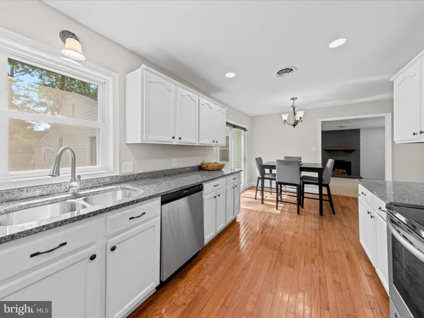a kitchen with granite countertop wooden floors and white cabinets