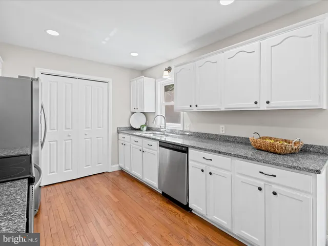 a kitchen with granite countertop white cabinets and white appliances
