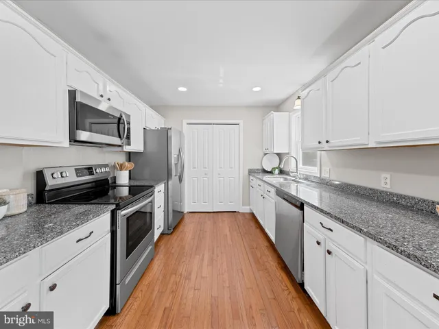 a large kitchen with stainless steel appliances granite countertop a stove sink and cabinets