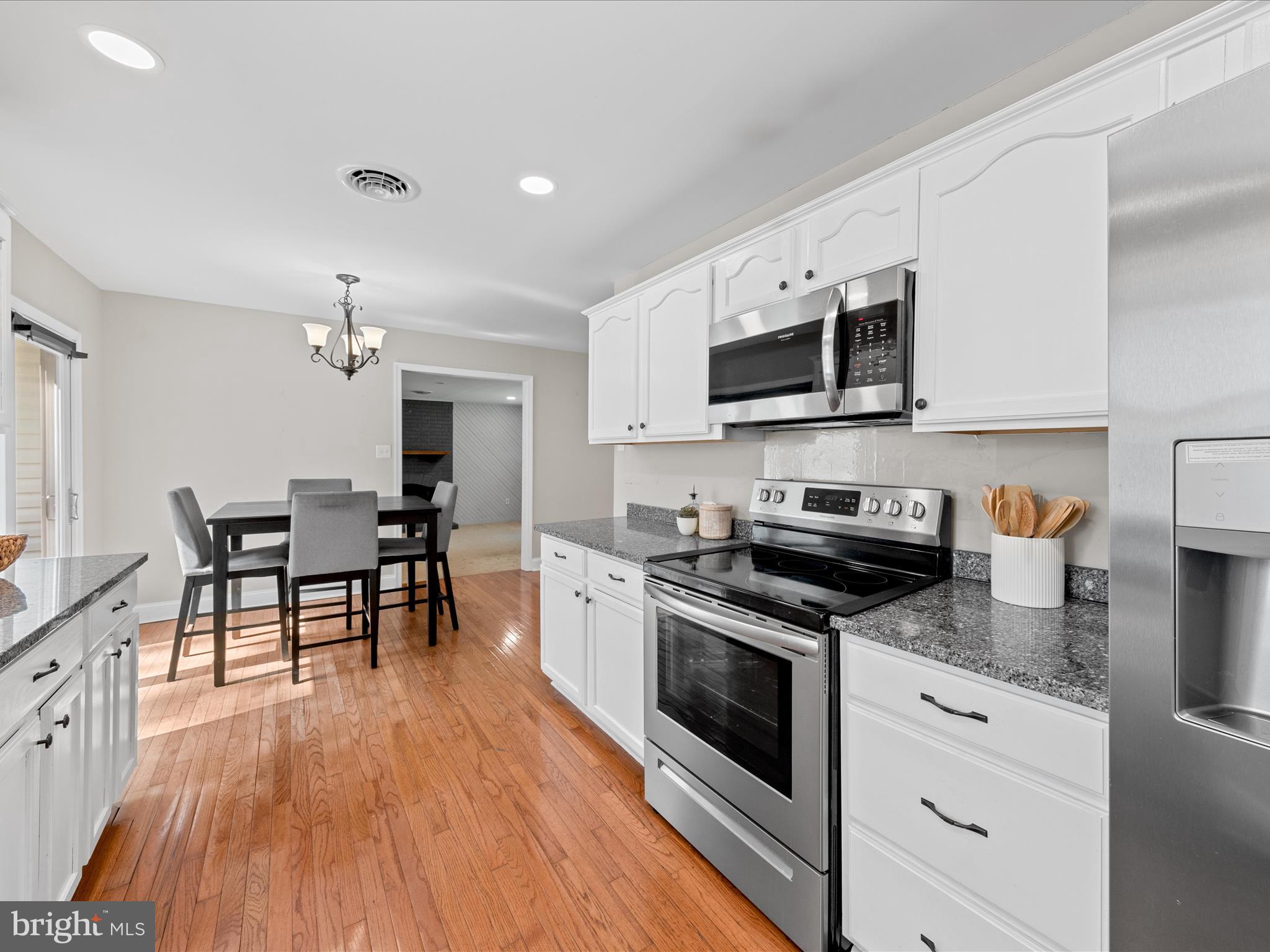 26831 River Road Seaford, DE 19973 - Photo 7 of 41 a kitchen with stainless steel appliances granite countertop a stove top oven a sink dishwasher a dining table and chairs with wooden floor