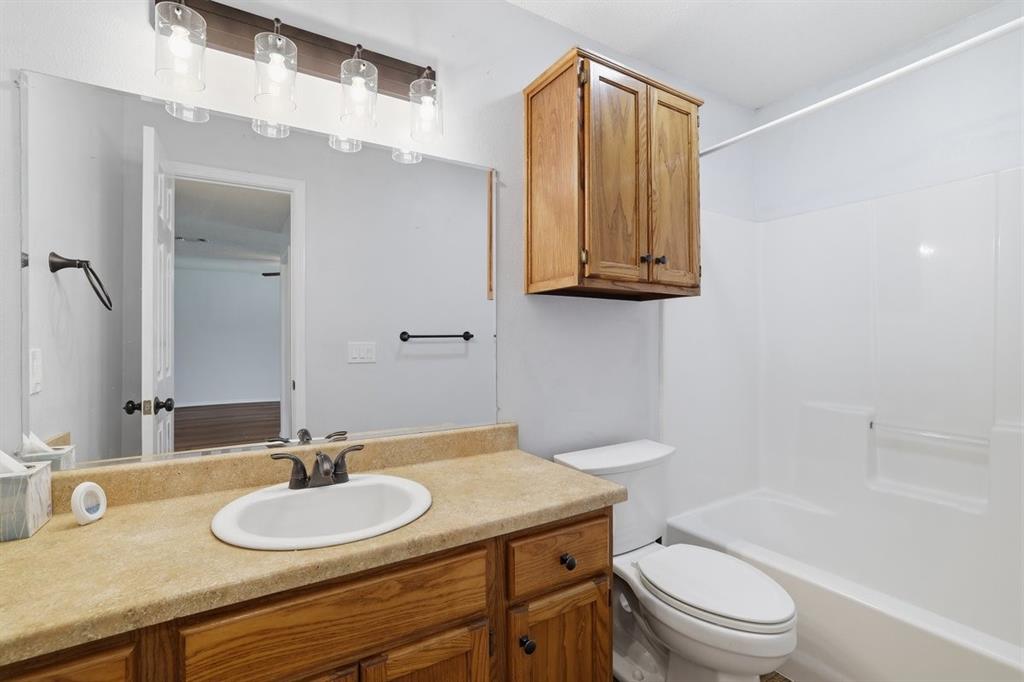1974 County Road Powderly, TX 75473 - Photo 21 of 28 a bathroom with a granite countertop sink toilet a mirror and bathtub