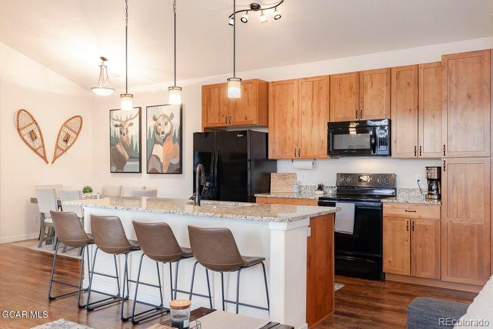 164 Village Road, Unit H304 Granby, CO 80446 - Photo 4 of 50 a kitchen with stainless steel appliances kitchen island granite countertop a stove a refrigerator a sink a dining table and chairs with wooden floor