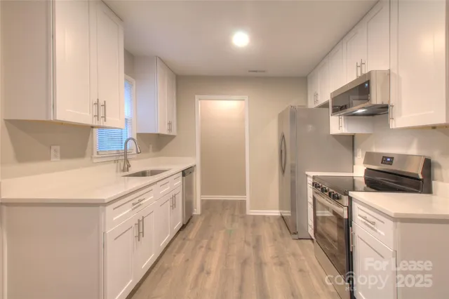 a kitchen with stainless steel appliances a sink stove refrigerator and cabinets