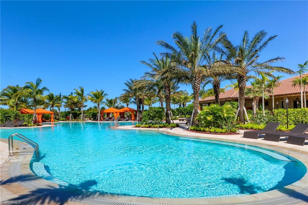 9366 Pocida Court, Unit 202 Naples, FL 34119 - Photo 31 of 44 a view of a swimming pool with a lawn chairs potted plants and palm tree