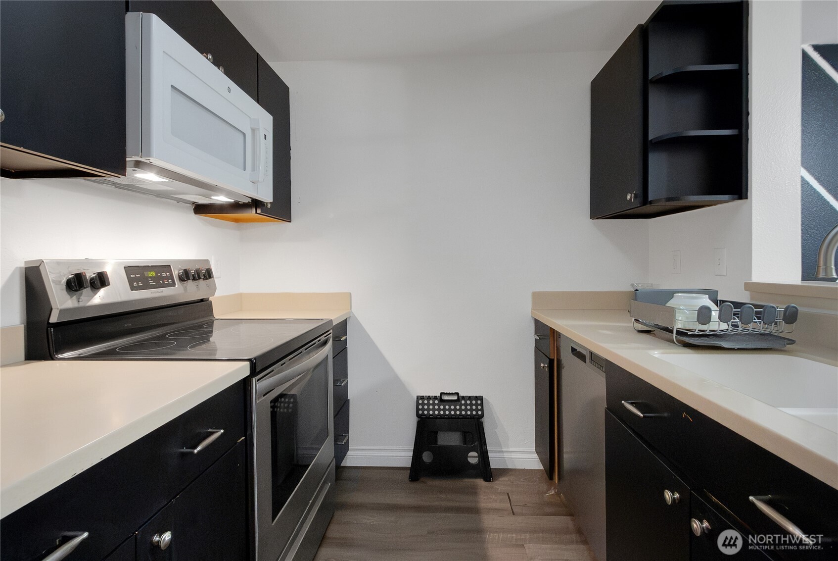 11002 Southeast Petrovitsky Road, Unit E103 Renton, WA 98055 - Photo 4 of 14 a kitchen with stainless steel appliances a sink dishwasher stove and microwave with wooden floor
