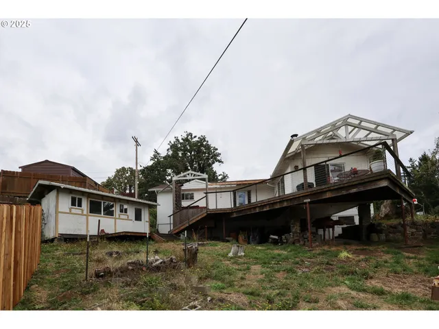 a view of a house with a wooden deck and a yard