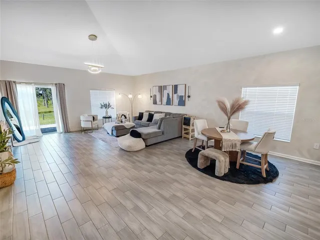 a living room with furniture hard wood floor and a large window