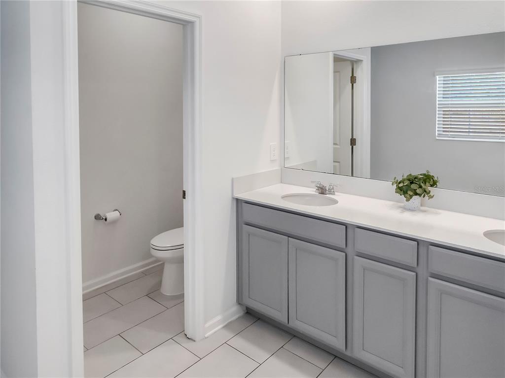 771 Hitch Loop St. Cloud, FL 34772 - Photo 25 of 34 a bathroom with a granite countertop sink a toilet and a mirror