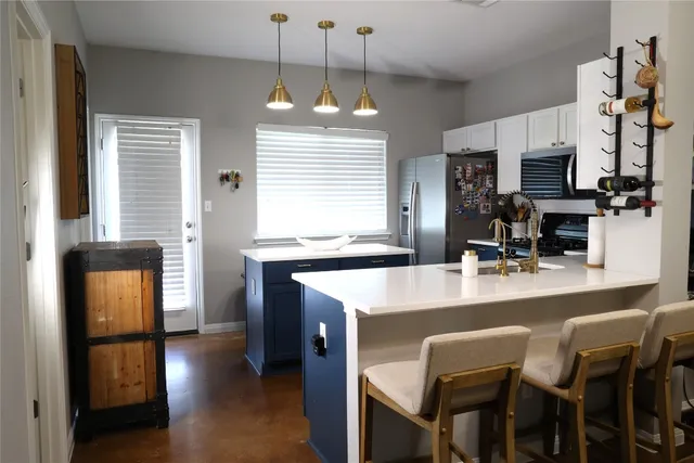 a kitchen with stainless steel appliances granite countertop a stove top oven a refrigerator a sink and a dining table with white cabinets