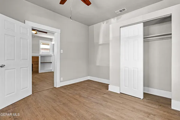 a view of an empty room with wooden floor and closet