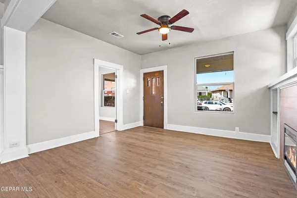an empty room with wooden floor ceiling fan and windows