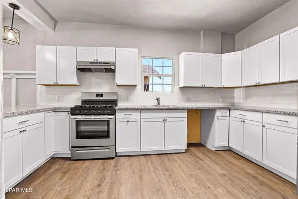 a kitchen with stainless steel appliances a white stove top oven cabinets and a wooden floor