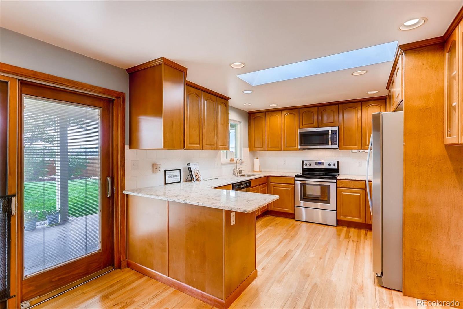 1458 South Oneida Street Denver, CO 80224 - Photo 12 of 33 a kitchen with stainless steel appliances granite countertop a refrigerator a stove top oven a sink and dishwasher with wooden floor