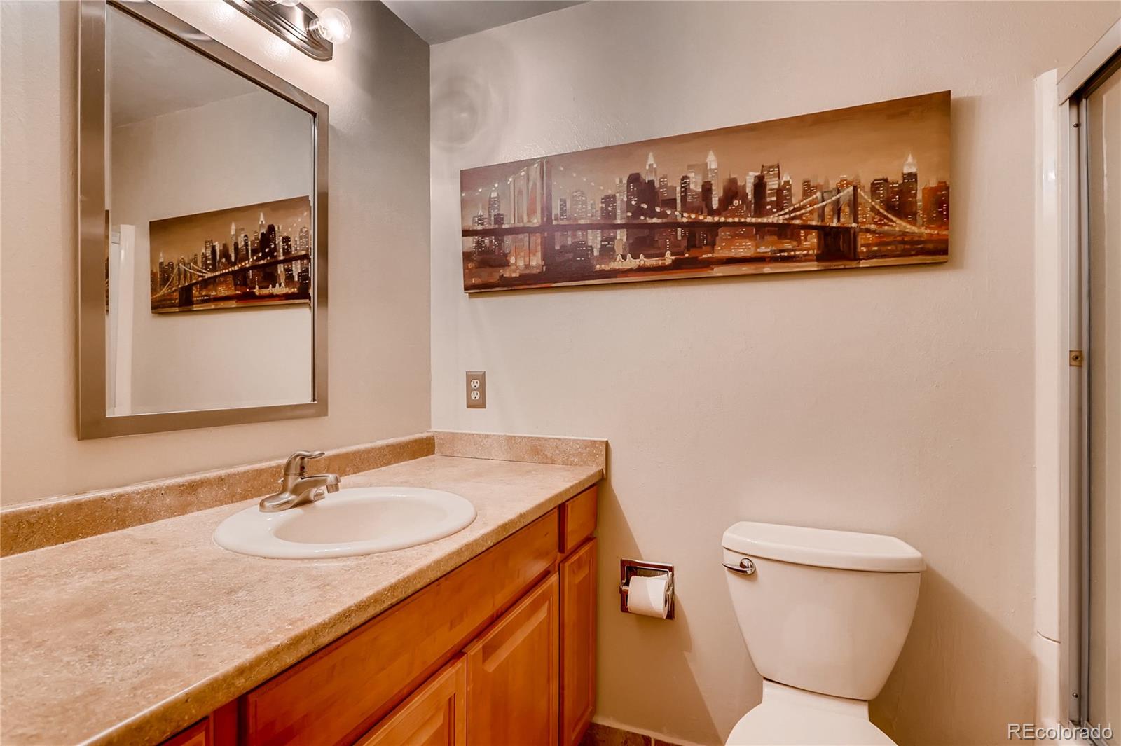 1458 South Oneida Street Denver, CO 80224 - Photo 18 of 33 a bathroom with a toilet a sink and mirror