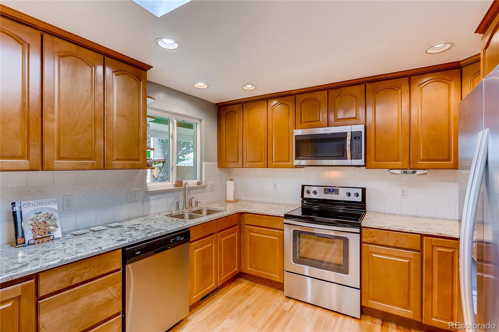 1458 South Oneida Street Denver, CO 80224 - Photo 10 of 33 a kitchen with granite countertop wooden cabinets stainless steel appliances and a sink
